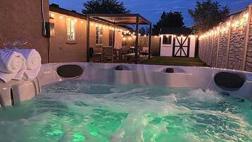 Un bain à remous avec un mur en pierre et un espace patio couvert.