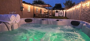 A hot tub with a stone wall and a covered patio area.
