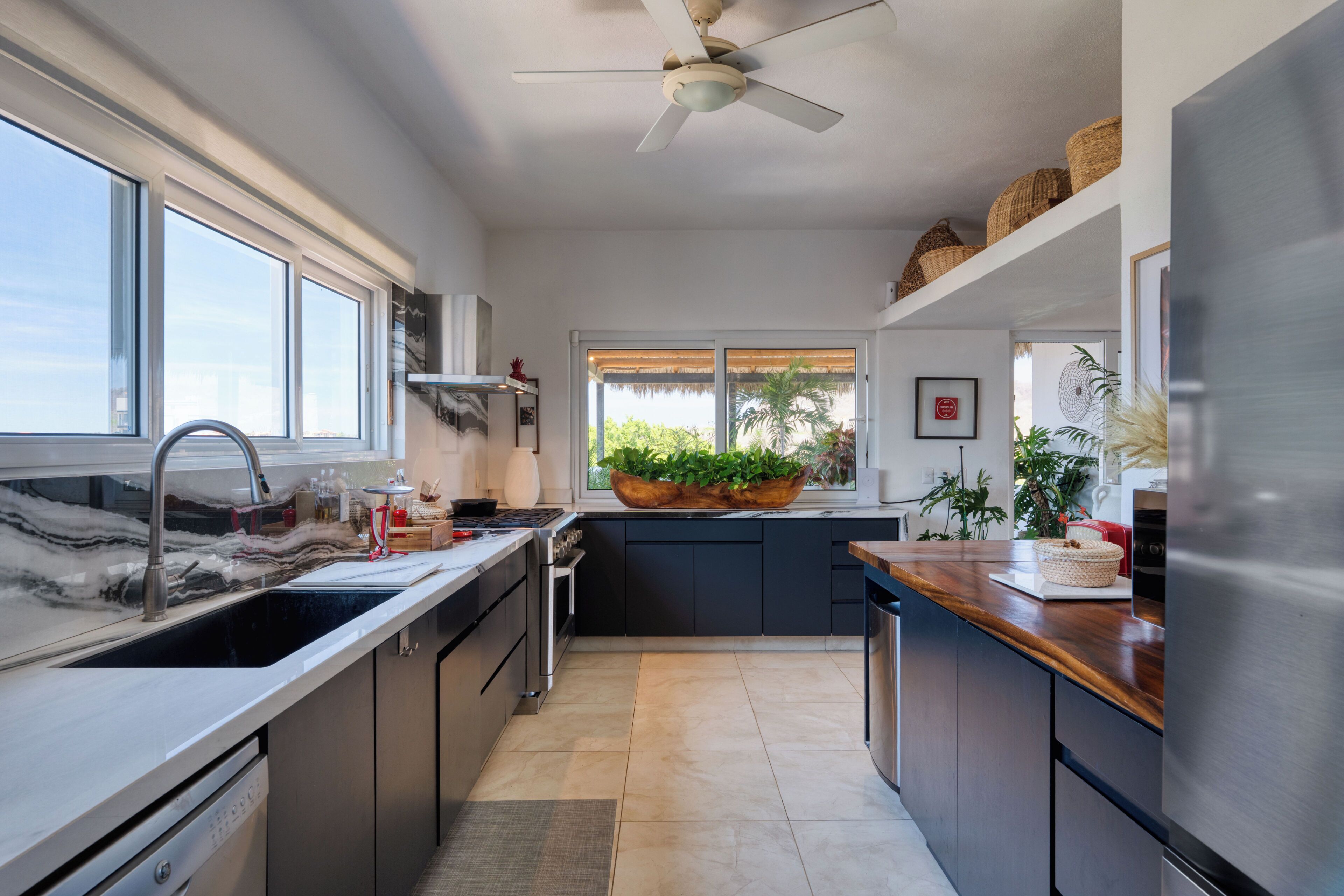 A modern kitchen with a large island, stainless steel appliances, and a view to the outdoors.