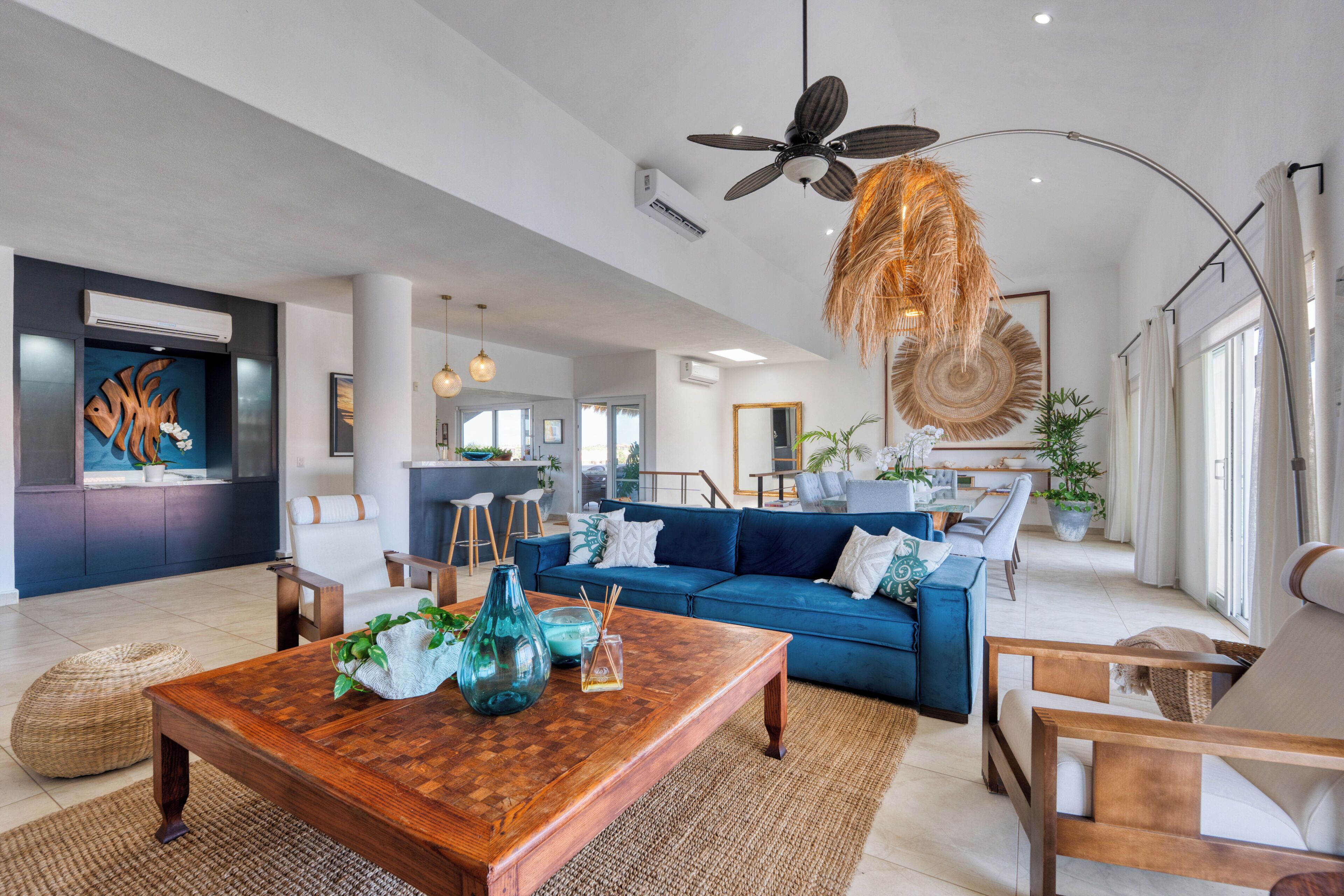 A spacious living area with a blue sofa, a wooden coffee table, and a hanging light fixture.