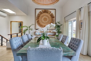 A modern dining area with a marble table, upholstered chairs, and decorative plants. - Luxury two-story penthouse condo at the beach in the heart of Punta de Mita! (Punta de Mita)