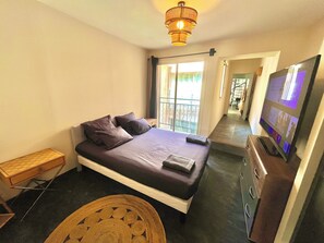 Ein Hotelzimmer mit einem Bett, einem Fernseher, einem Nachttisch aus Holz und Blick ins Freie.