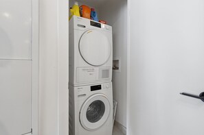 Waschmaschine und Trockner übereinander in einem Waschraum, mit einem Türgriff auf der rechten Seite.