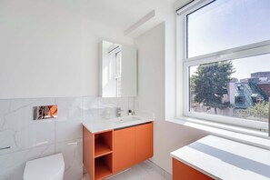 A modern bathroom with a white sink, mirror, and toilet. - 114 Cook - Loft in the Heart of Old Quebec (Québec)
