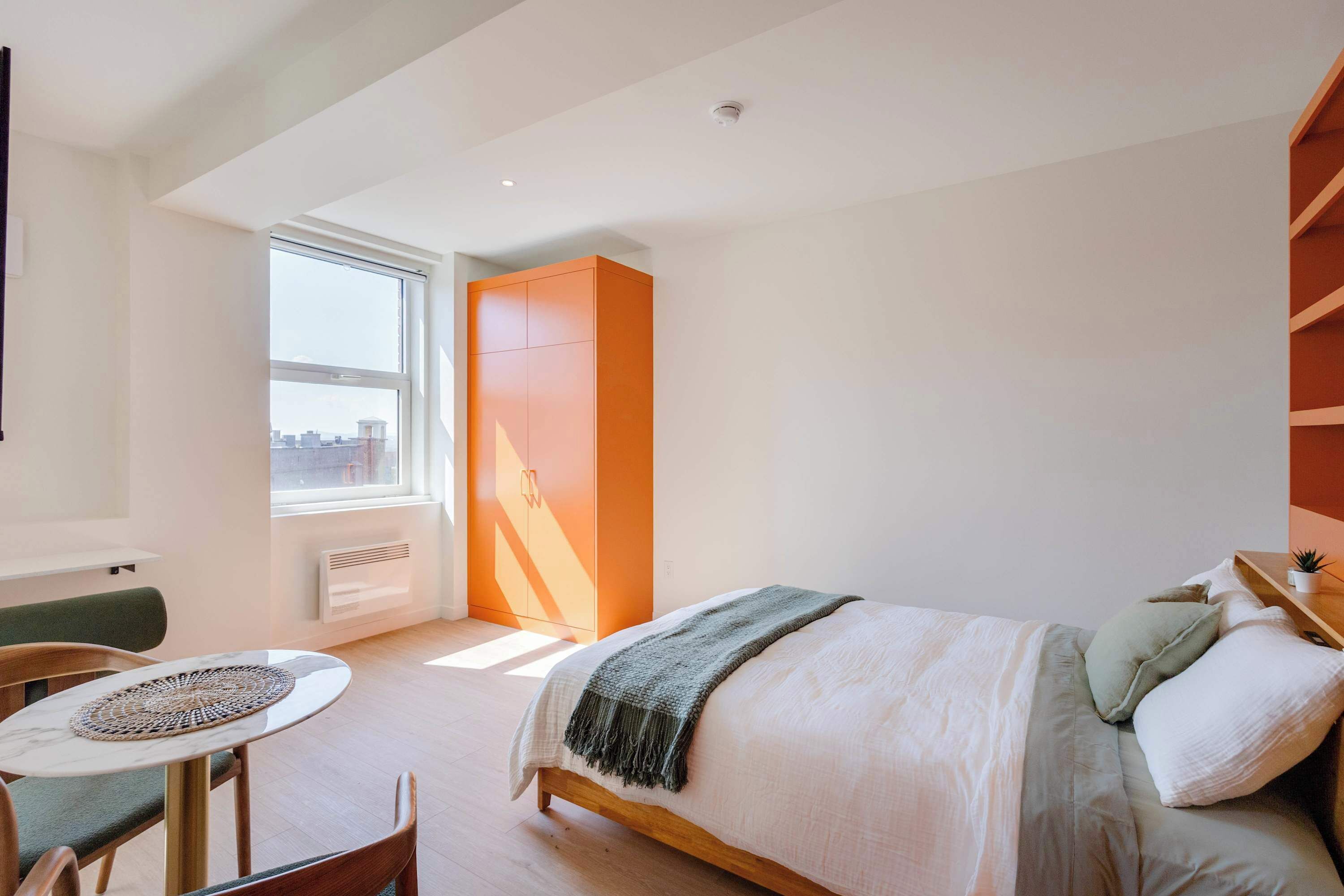 A modern bedroom with a bed, a small table, and a chair.