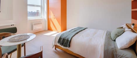 A modern bedroom with a bed, a small table, and a chair.