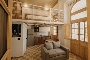 A compact living space with a kitchenette, a sofa, and a checkered floor. - San Felipe 668 (Guadalajara)
