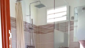 A bathroom with a glass shower enclosure, a toilet, a sink, and a mirror. - BEAUVALETTE SOLEIL (Sainte-Anne)