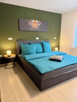 A bedroom with a bed, two bedside tables, a wall-mounted artwork, and a window. - Westerhäuser Vacation Rentals – Apartment Schmuckstück – Family Apartment in the Harz Mountains (Thale)