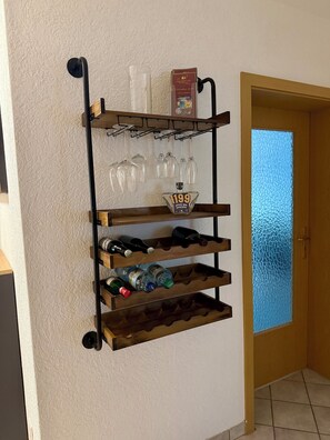 Ett vinställ som monteras på väggen och har flera hyllor för vinflaskor och vinglas.