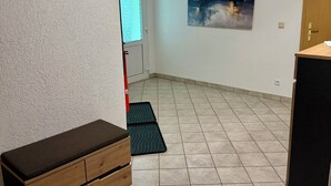 Une pièce avec un banc, une porte, un tableau accroché au mur et un sol carrelé.