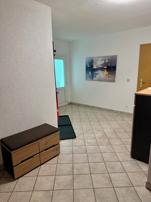 Ein Zimmer mit einer Bank, einer Tür, einem Wandbild und einem Fliesenboden.
