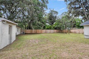A backyard with a wooden fence, a small shed, and a house. - The Lightkeeper's Cottage Beaufort, SC (Beaufort)