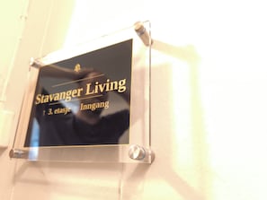 Ein Schild mit der Aufschrift 'Stavanger Living' und '3. Etage Eingang', das einen Ort oder eine Einrichtung kennzeichnet.