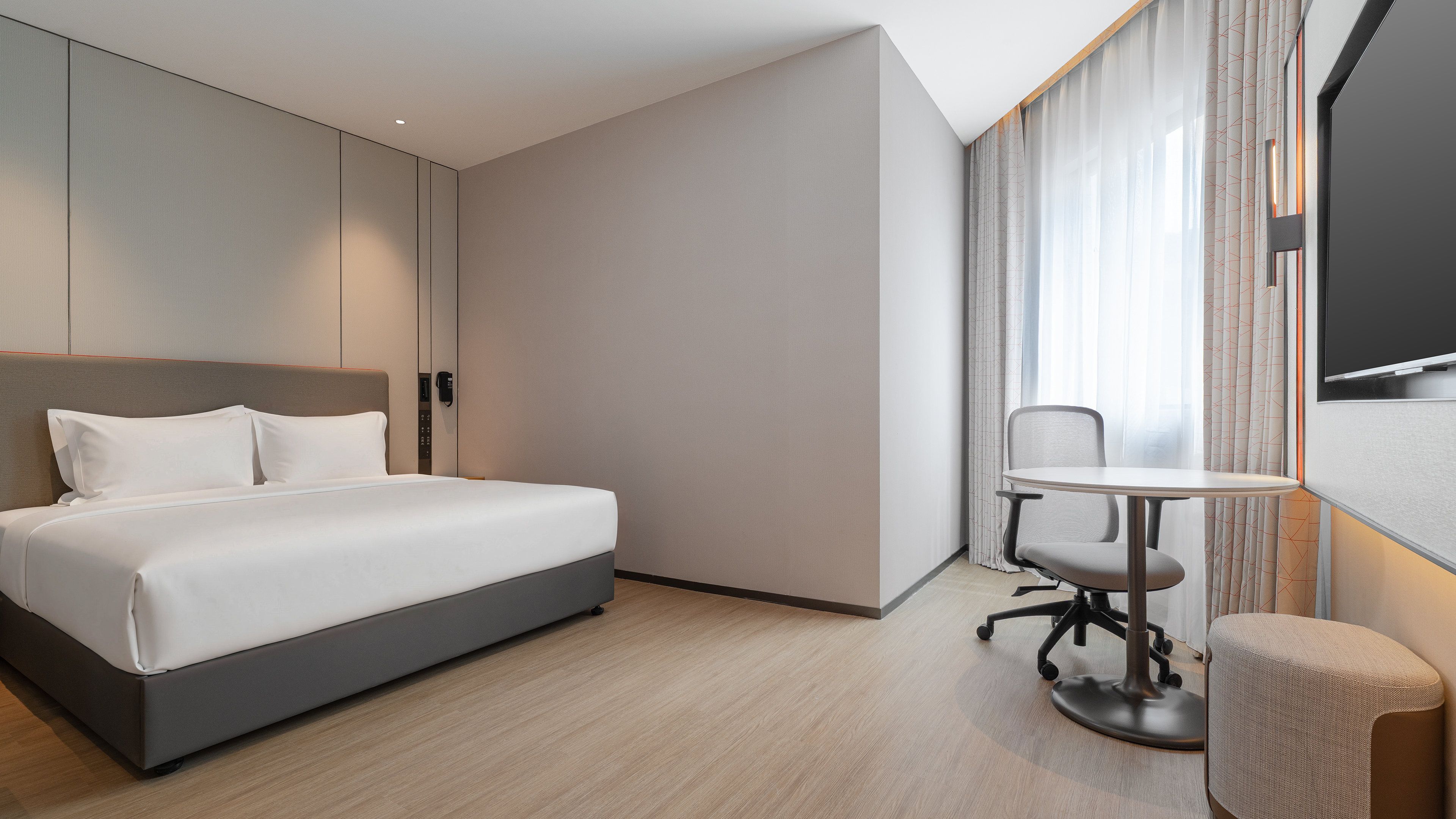 A hotel room with a bed, a desk, and a chair.
