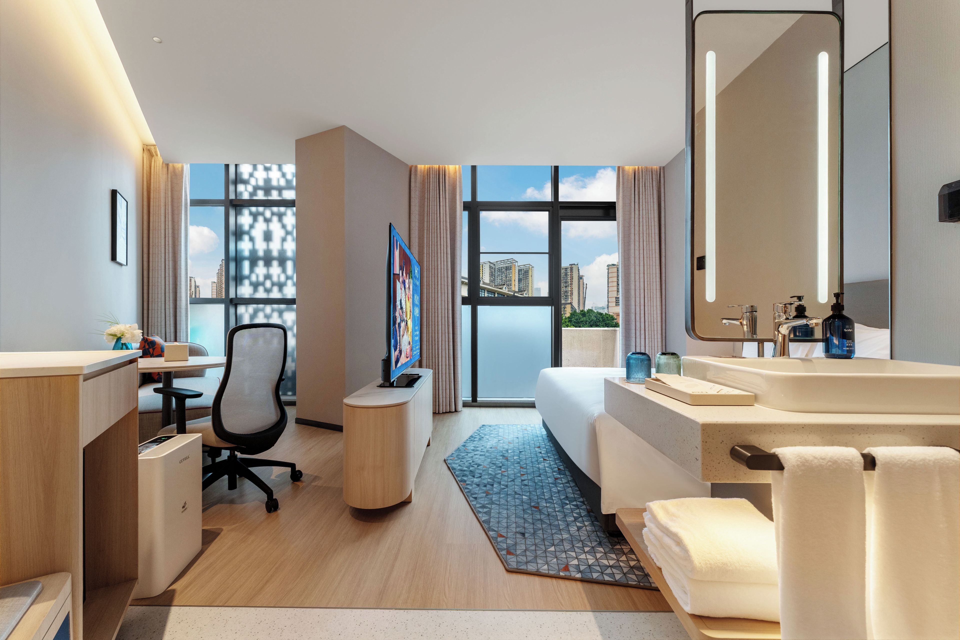 Habitación de hotel moderna con escritorio, silla, cama y baño.