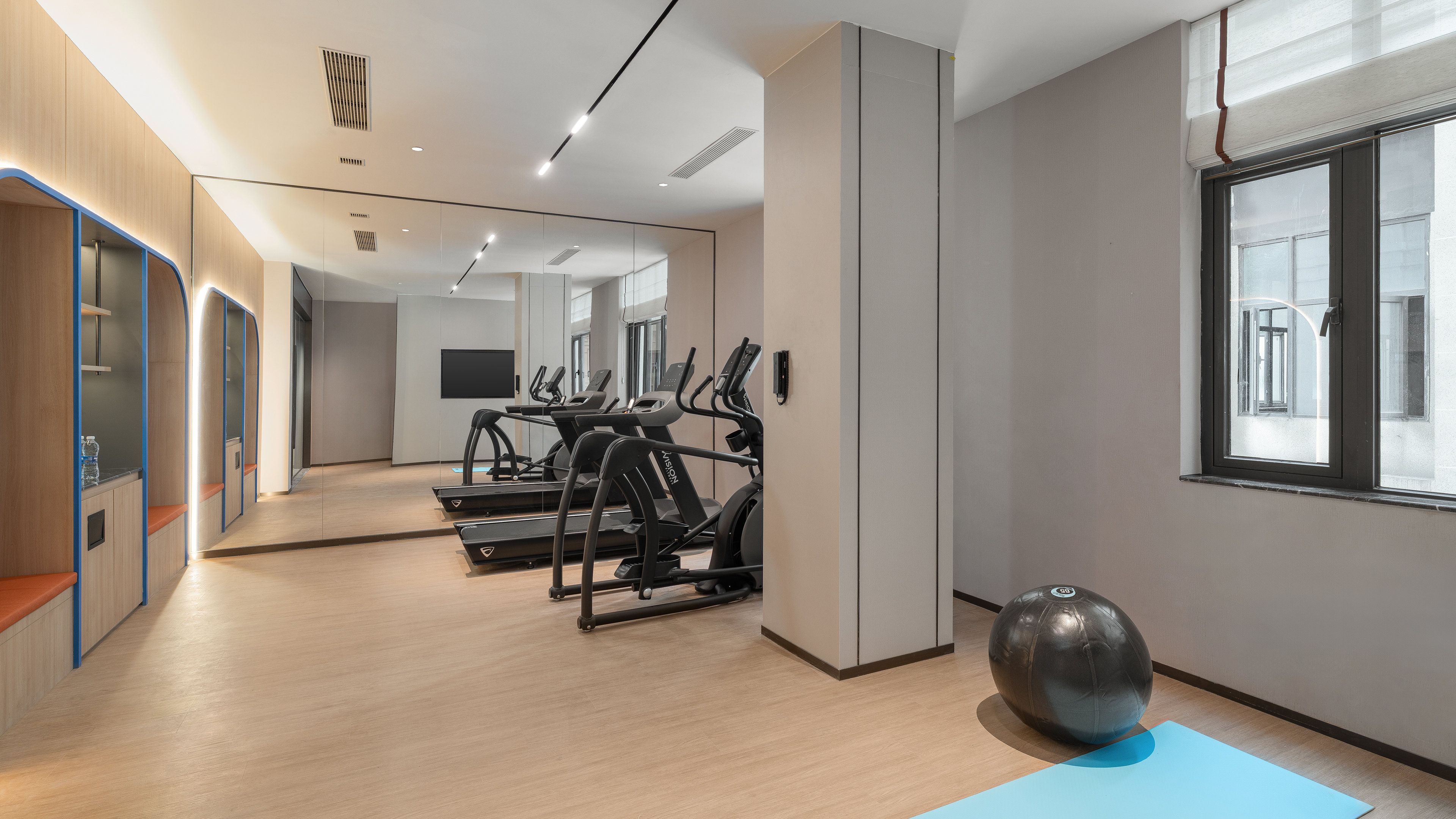A modern gym with treadmills, a stationary bike, and a large exercise ball.