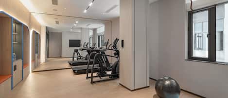 A modern gym with treadmills, a stationary bike, and a large exercise ball.