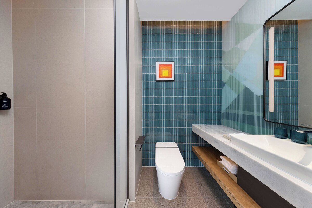 A modern bathroom with a shower, toilet, and sink.