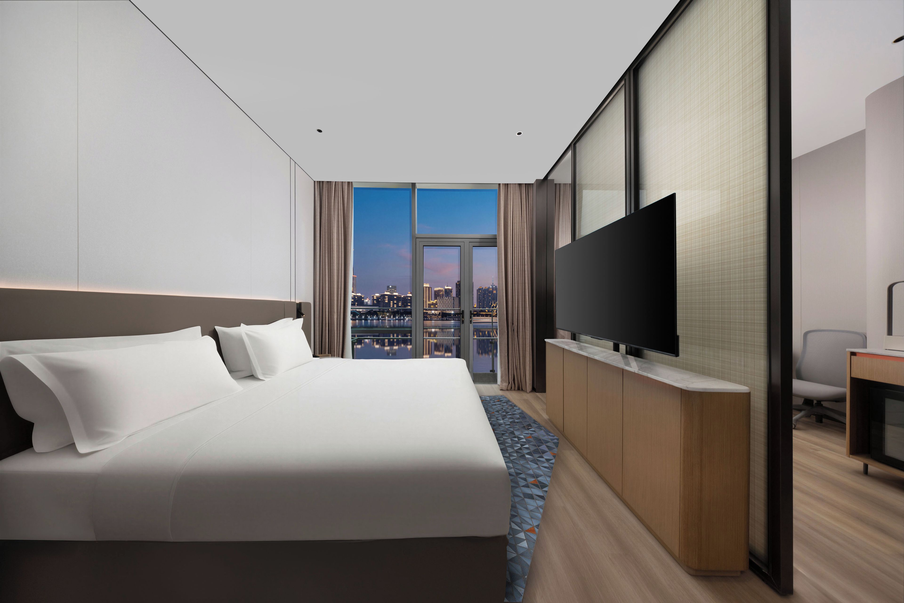 Quarto de hotel com uma cama grande, televisão de tela plana e vista para a cidade.