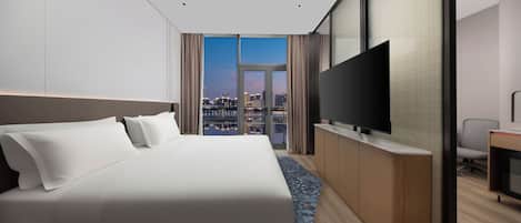 A hotel room with a large bed, a flat-screen TV, and a city view.