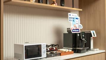 A coffee station with a sign reading 'COFFEE STATION,' a microwave, a coffee machine, and a kettle on the counter.