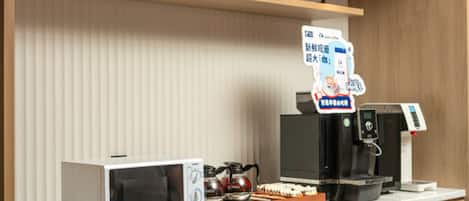 A coffee station with a sign reading 'COFFEE STATION,' a microwave, a coffee machine, and a kettle on the counter.