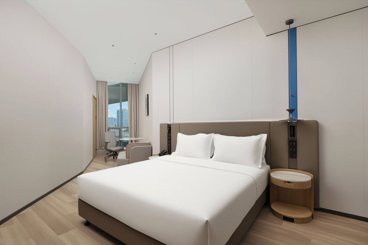 Una habitació d'hotel moderna amb un llit gran, una taula de treball i una cadira.