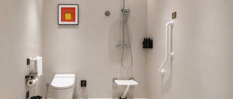 A modern bathroom with a toilet, shower, and a framed picture on the wall.