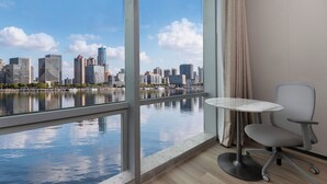A modern hotel room with a large window offering a city skyline view over a body of water. - Holiday Inn Express Shanghai North Bund Riverside By Ihg (Shanghai)