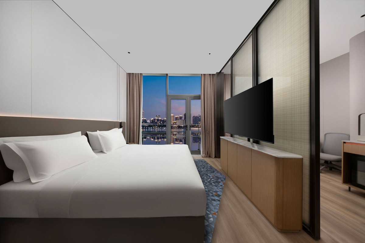 Una habitación de hotel con una cama grande, televisión de pantalla plana y vistas a la ciudad.