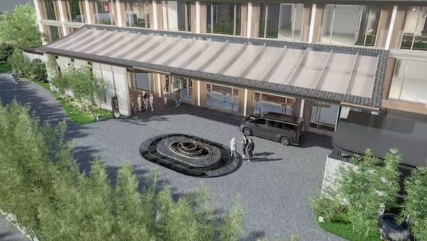 En modern byggnad med en överbyggd entré, en rundad uppfart och en bil parkerad utanför.
