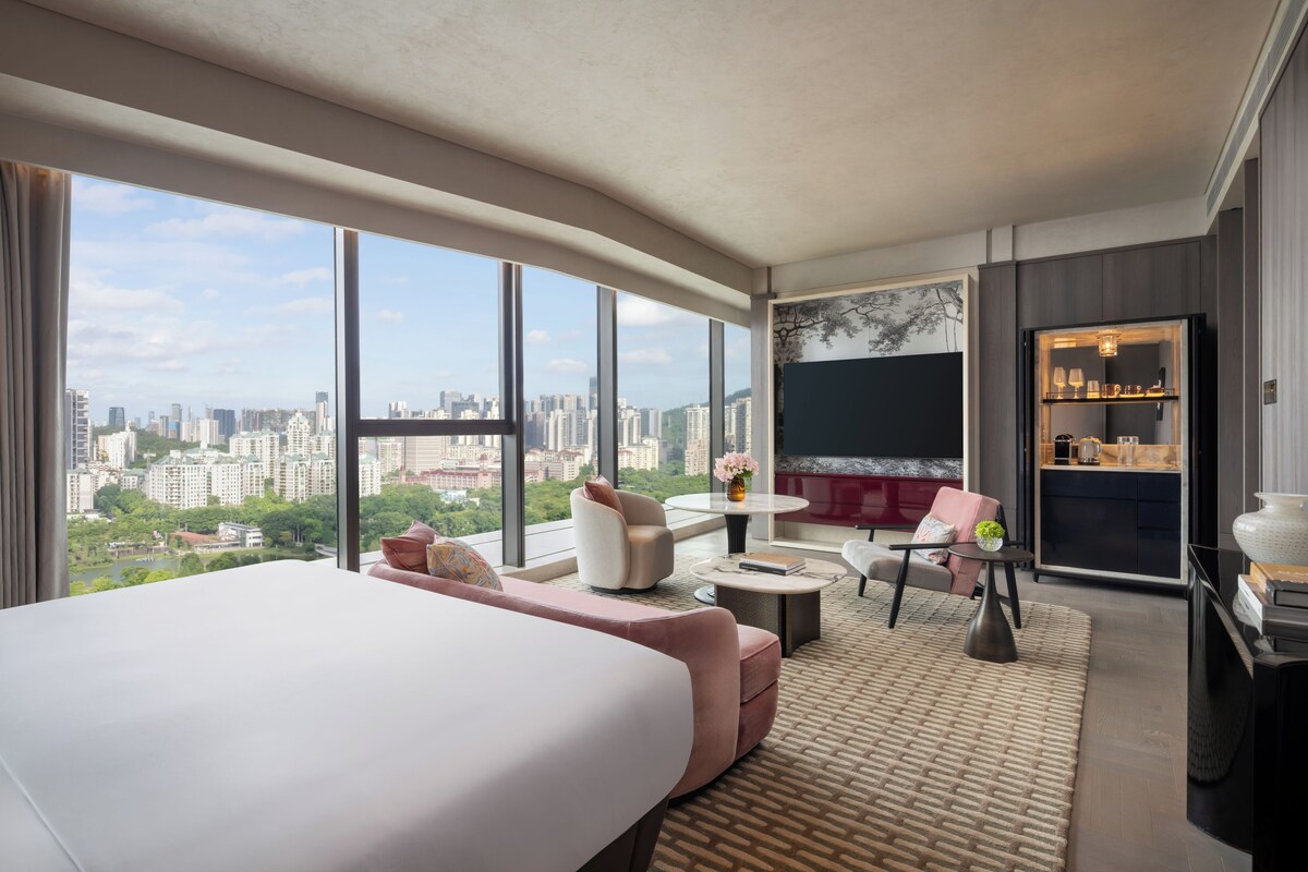 Ein modernes Hotelzimmer mit einem großen Bett, einer Sitzecke und Blick auf die Stadt.