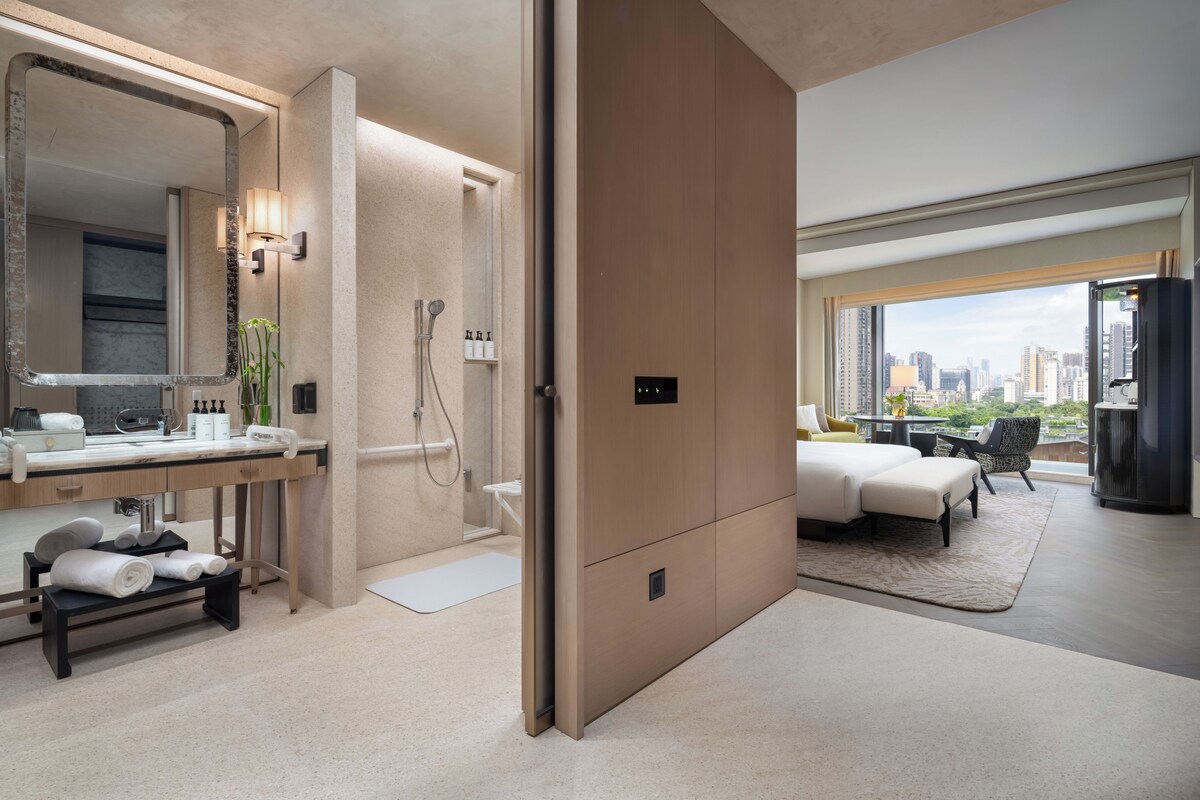 Ein modernes Hotelzimmer mit Bad, einem Bett und Blick auf die Stadt.