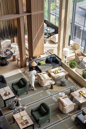 Un vestíbulo de hotel espacioso con varias zonas de estar, una mesa de centro y vistas al exterior.