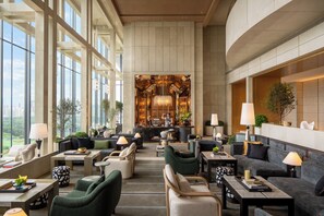 Eine geräumige Lobby mit hohen Decken, großen Fenstern und einer Bar.