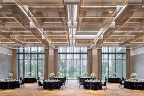 Una amplia sala de conferencias con varias mesas, grandes ventanales y un diseño moderno de techo.