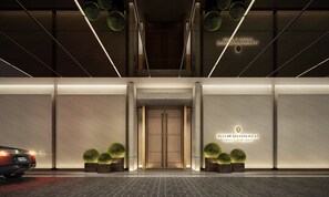 Ein moderner Hotelzugang mit Doppeltüren, beleuchteter Beschilderung und symmetrischer Bepflanzung.