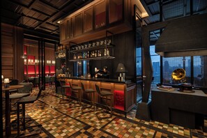 Un área de bar con piso a cuadros, taburetes y un jukebox.