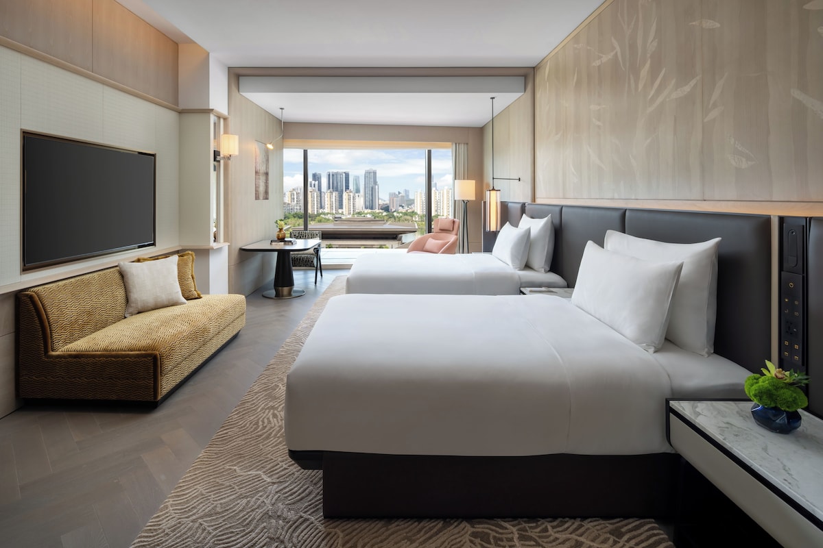 Ein modernes Hotelzimmer mit einem großen Bett, einer Couch, einem Schreibtisch und einem Fernseher.