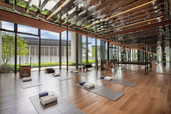 Una habitación amplia con ventanas grandes, piso de madera y equipo de ejercicio.
