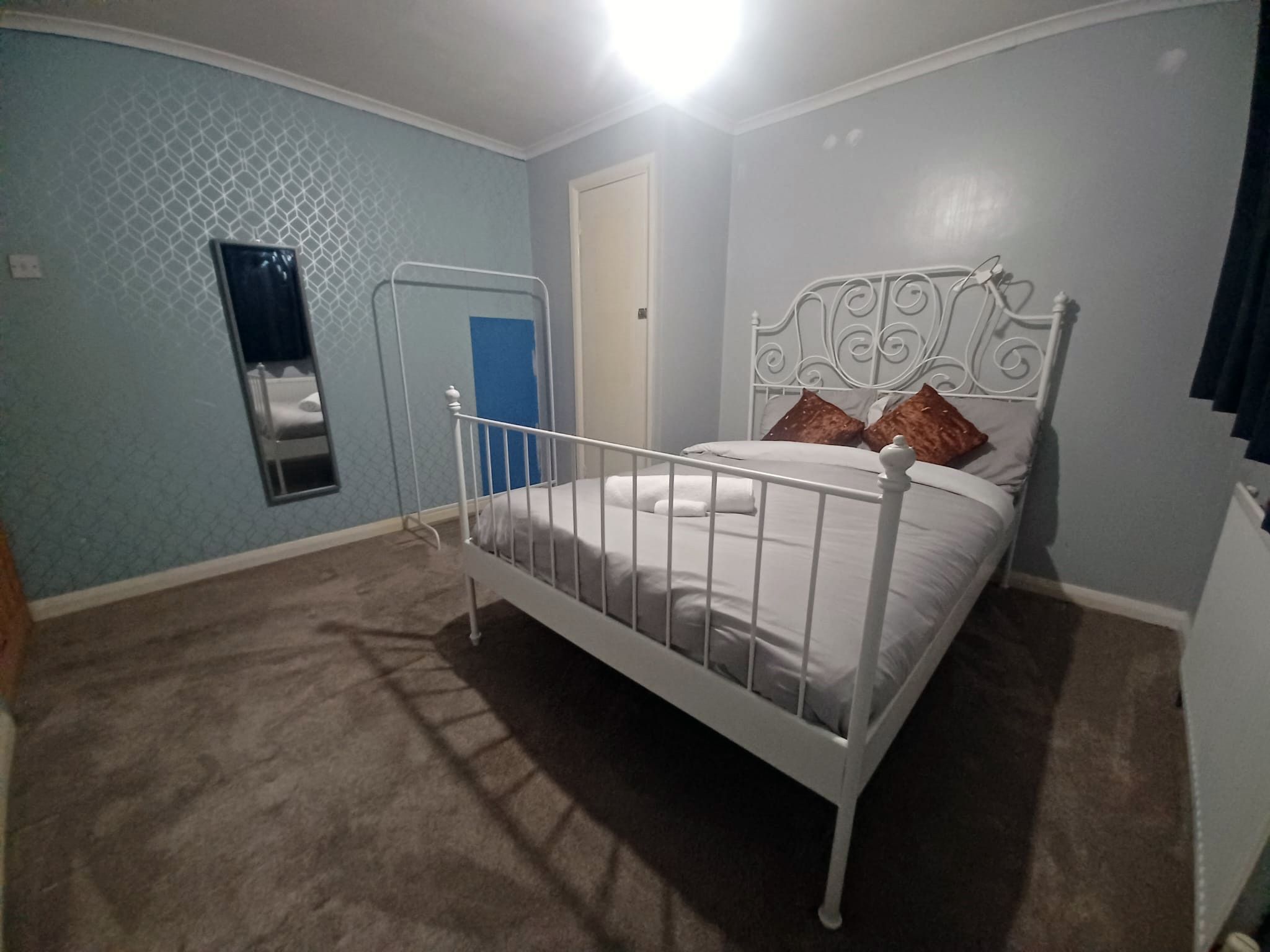 Un dormitorio con una cama individual, una puerta y un ventanal.