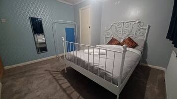 Un dormitorio con una cama individual, una puerta y un ventanal.
