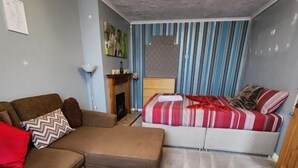 Een woonkamer met een bank, een houten salontafel, een gestreepte wand en een open haard.