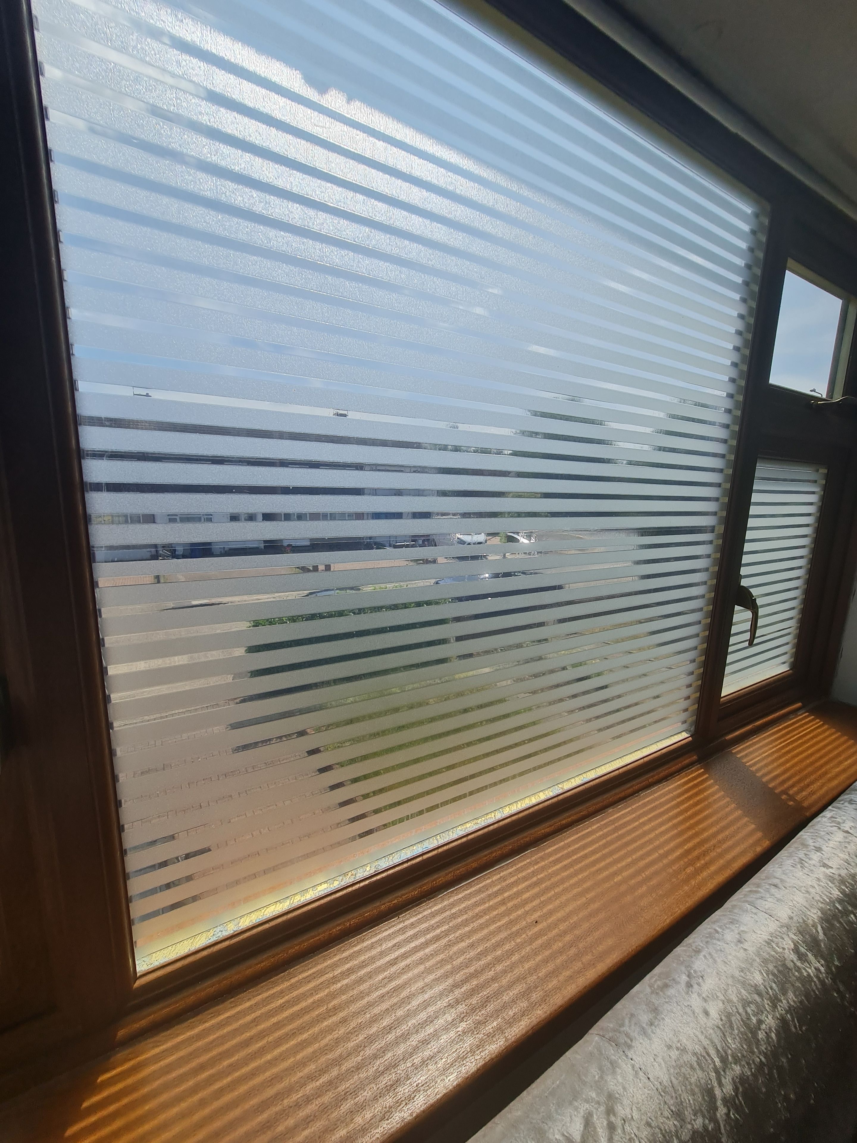 Una ventana con persianas horizontales y vista a un edificio.