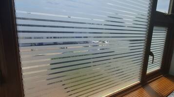 Una ventana con persianas horizontales y vista a un edificio.