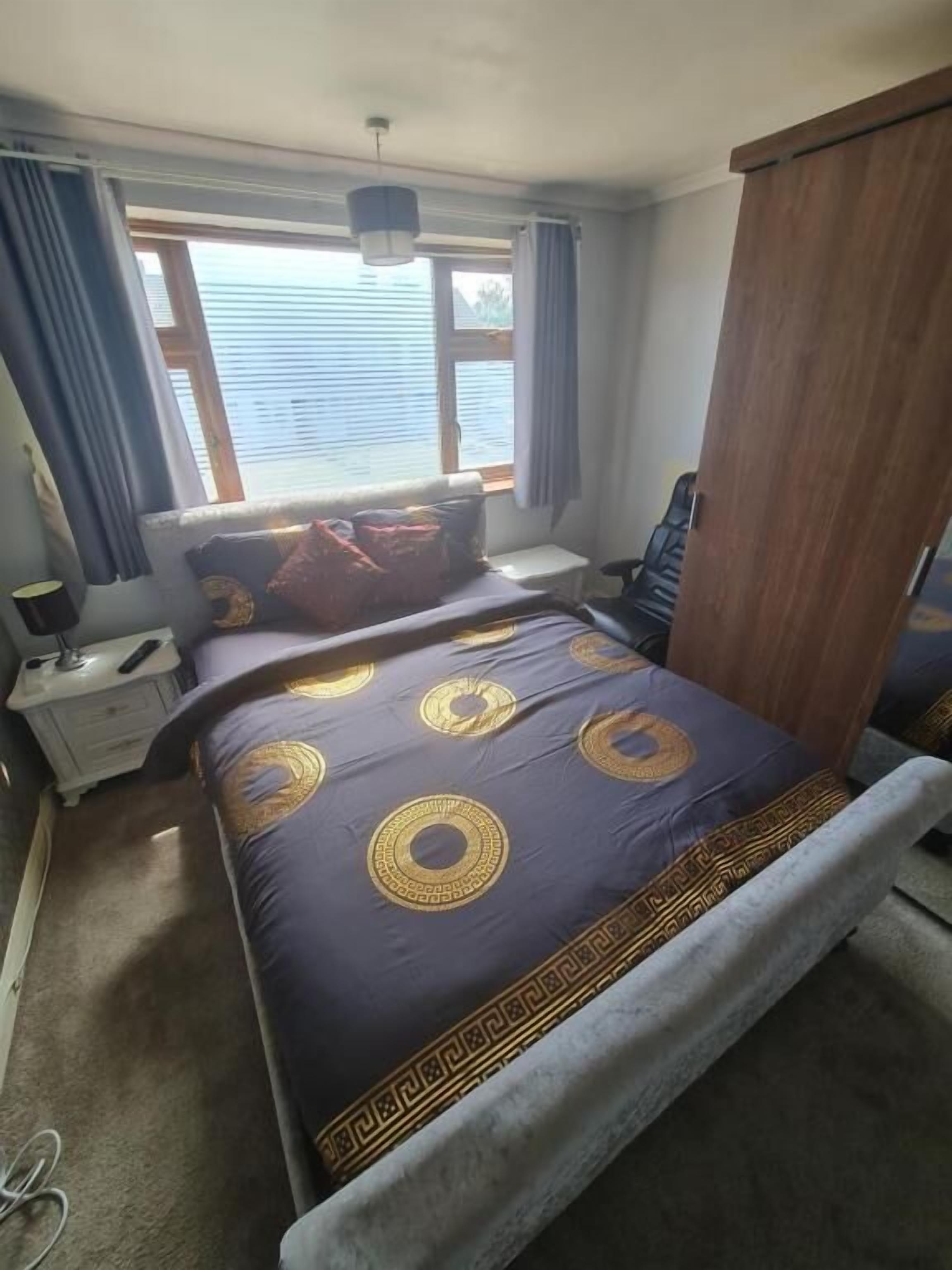 A bedroom with a bed, a nightstand, a lamp, and a window with curtains.