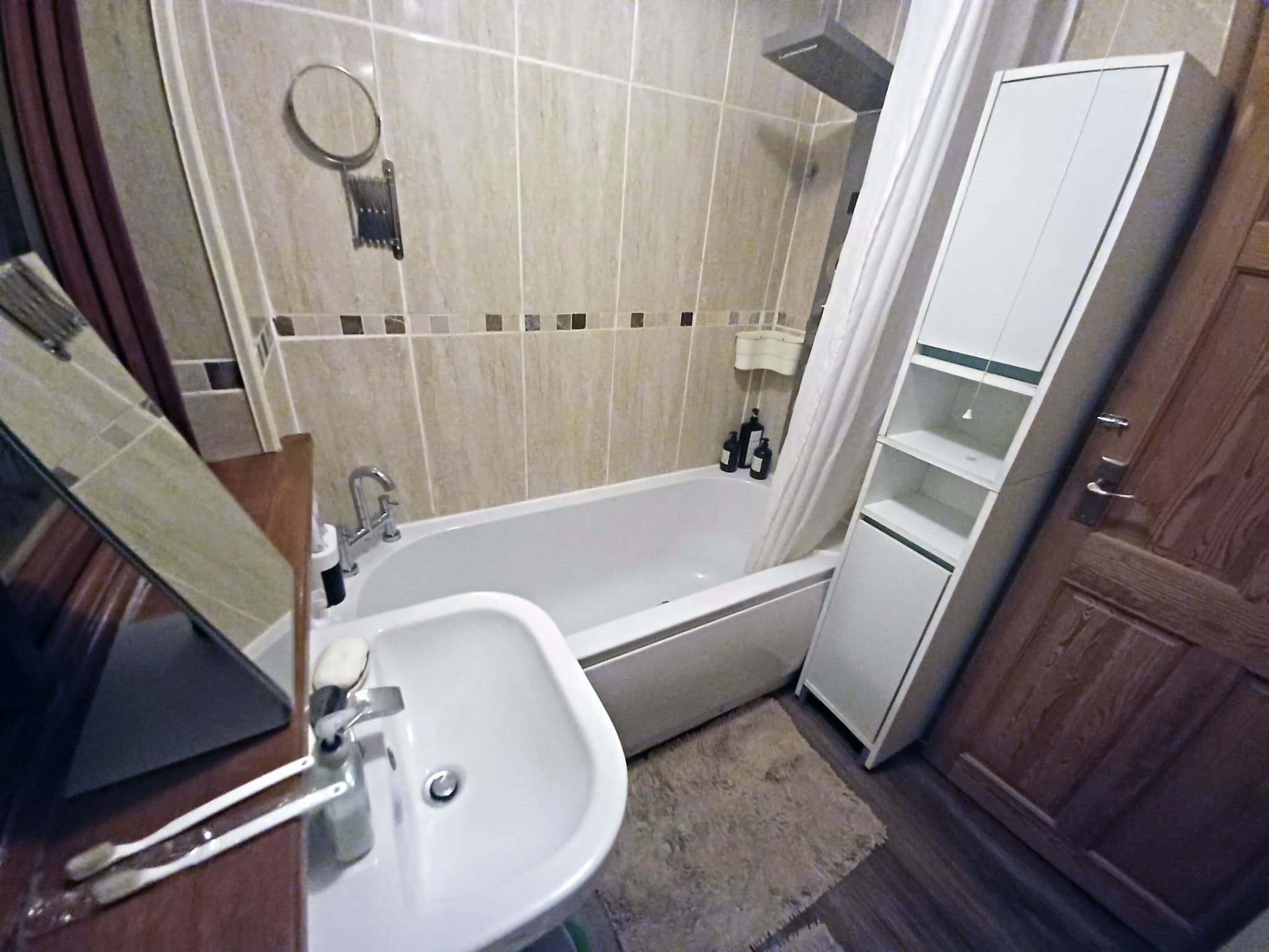 A bathroom with a bathtub, a sink, and a mirror.