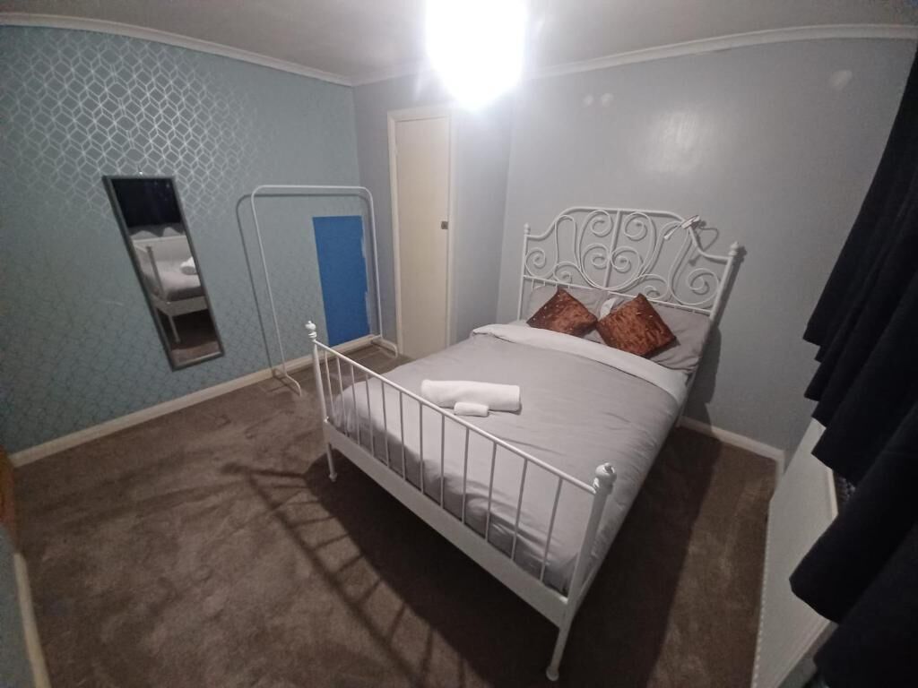 A bedroom with a metal-framed bed, a small window, and a door.