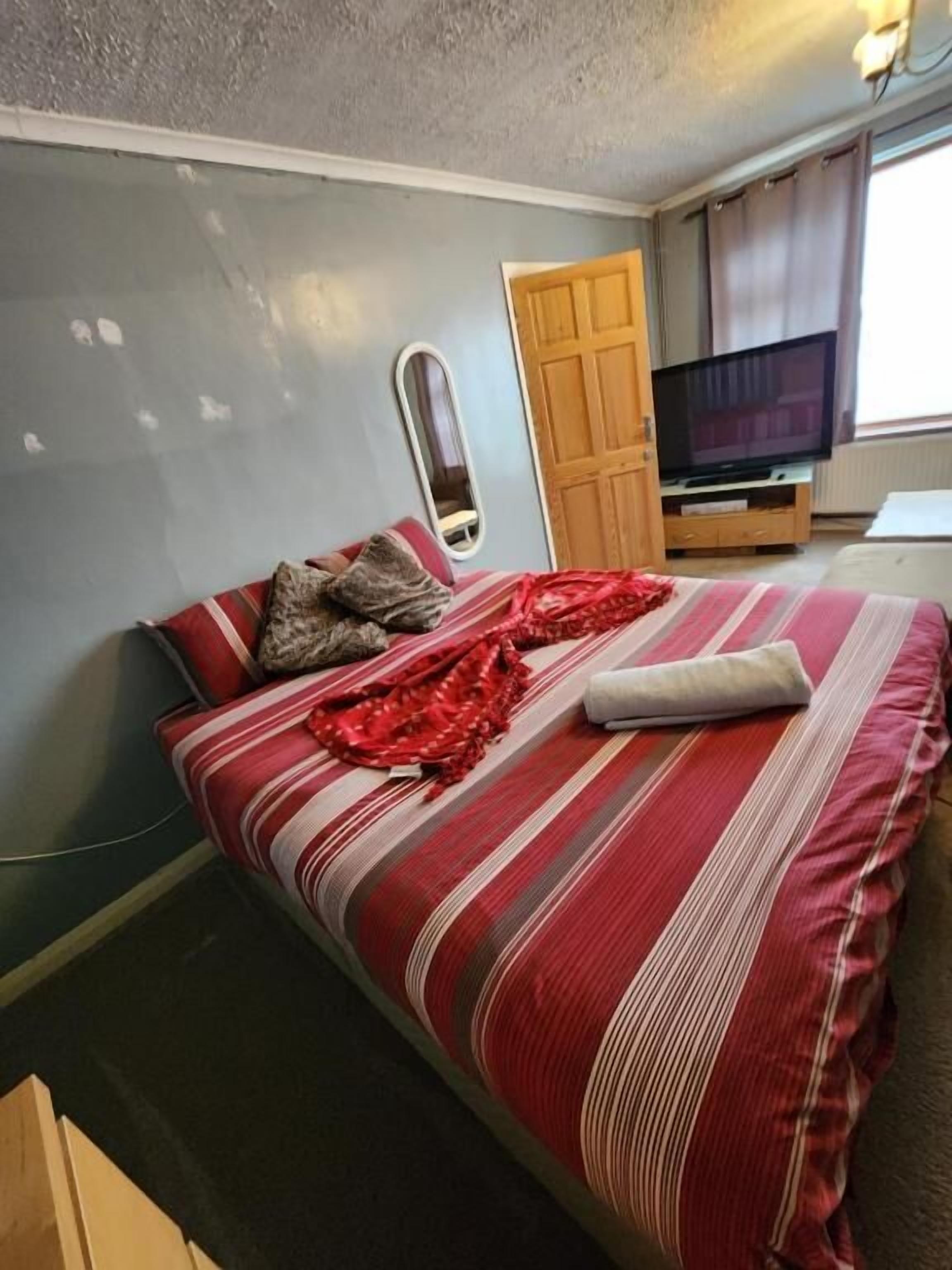 A bedroom with a bed, a television, and a wooden door.